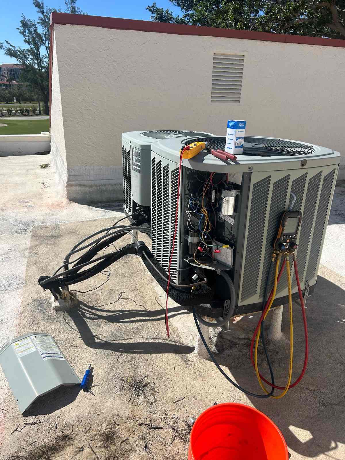 Outdoor AC condenser with its service panel open and a gauge attached during a repair in Pinellas County, FL