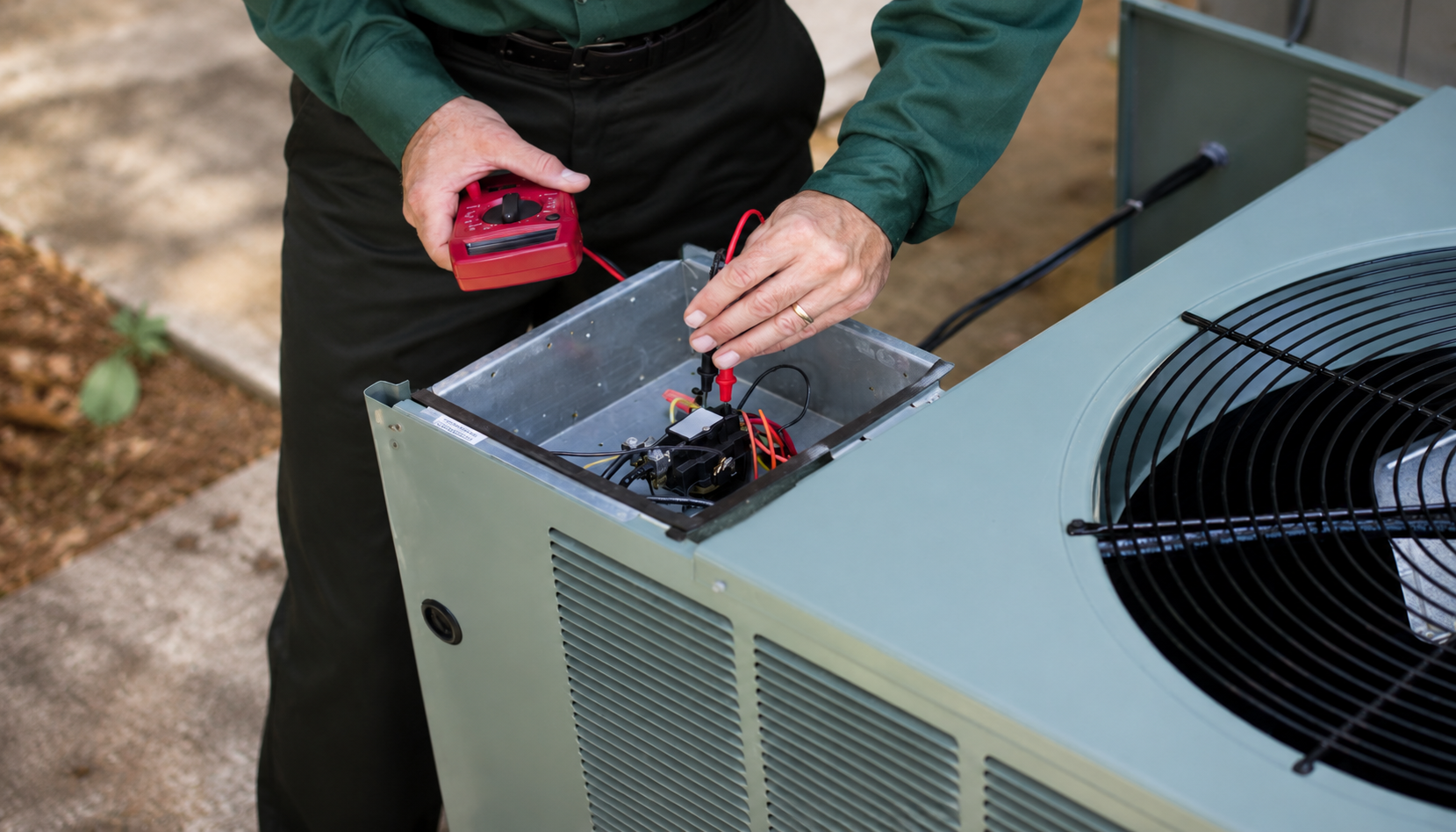 Technician checking the electrical components of an outdoor AC unit during AC maintenance