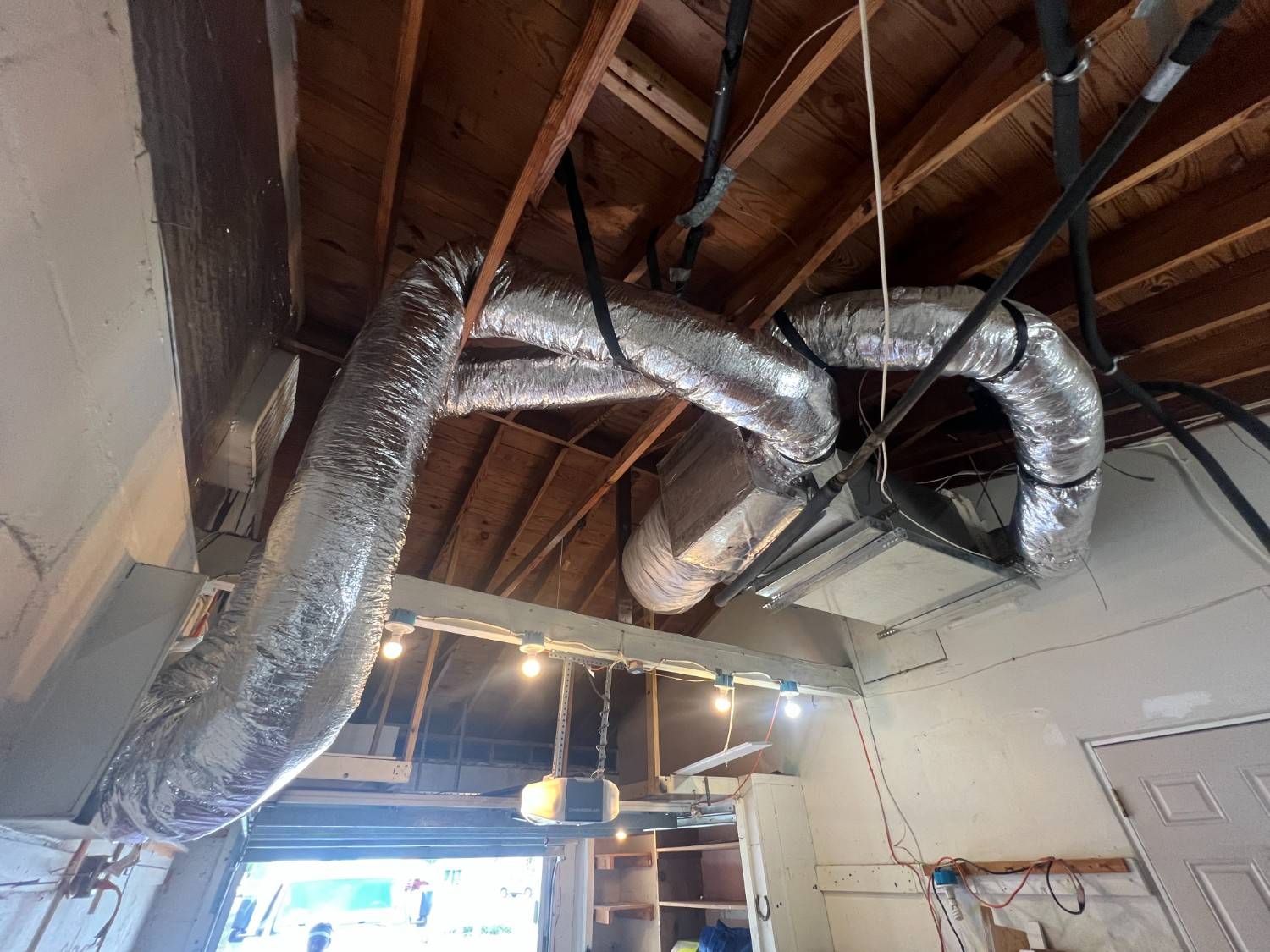 Newly installed insulated flex ductwork running through a ceiling