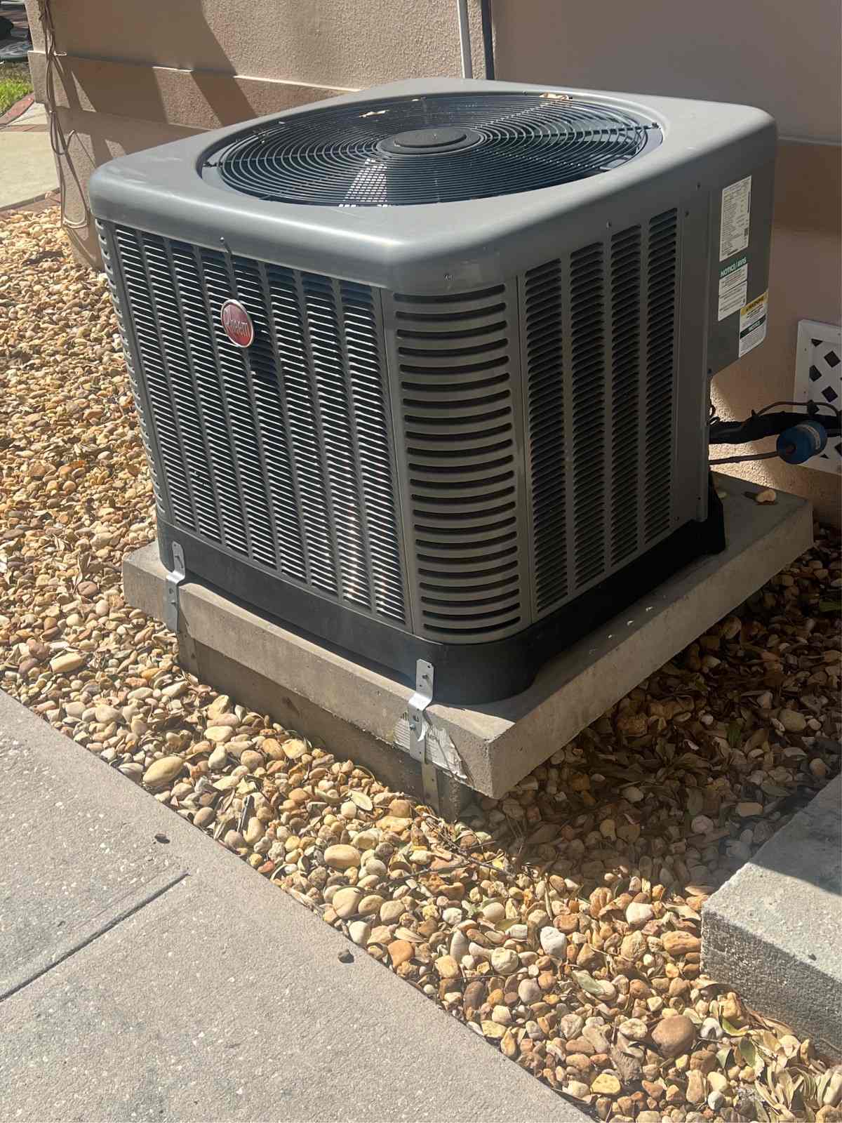 New heat pump outdoor unit installed on a gravel pad beside a Pinellas County, FL home