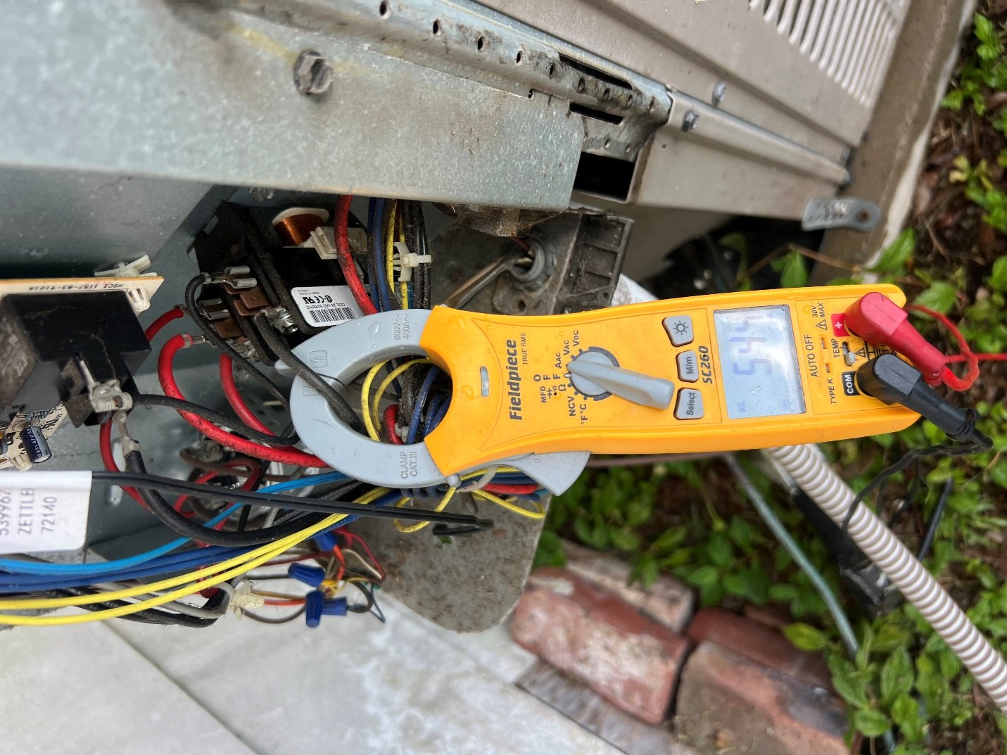 Clamp meter testing the electrical wiring of an outdoor AC unit in St. Petersburg, FL