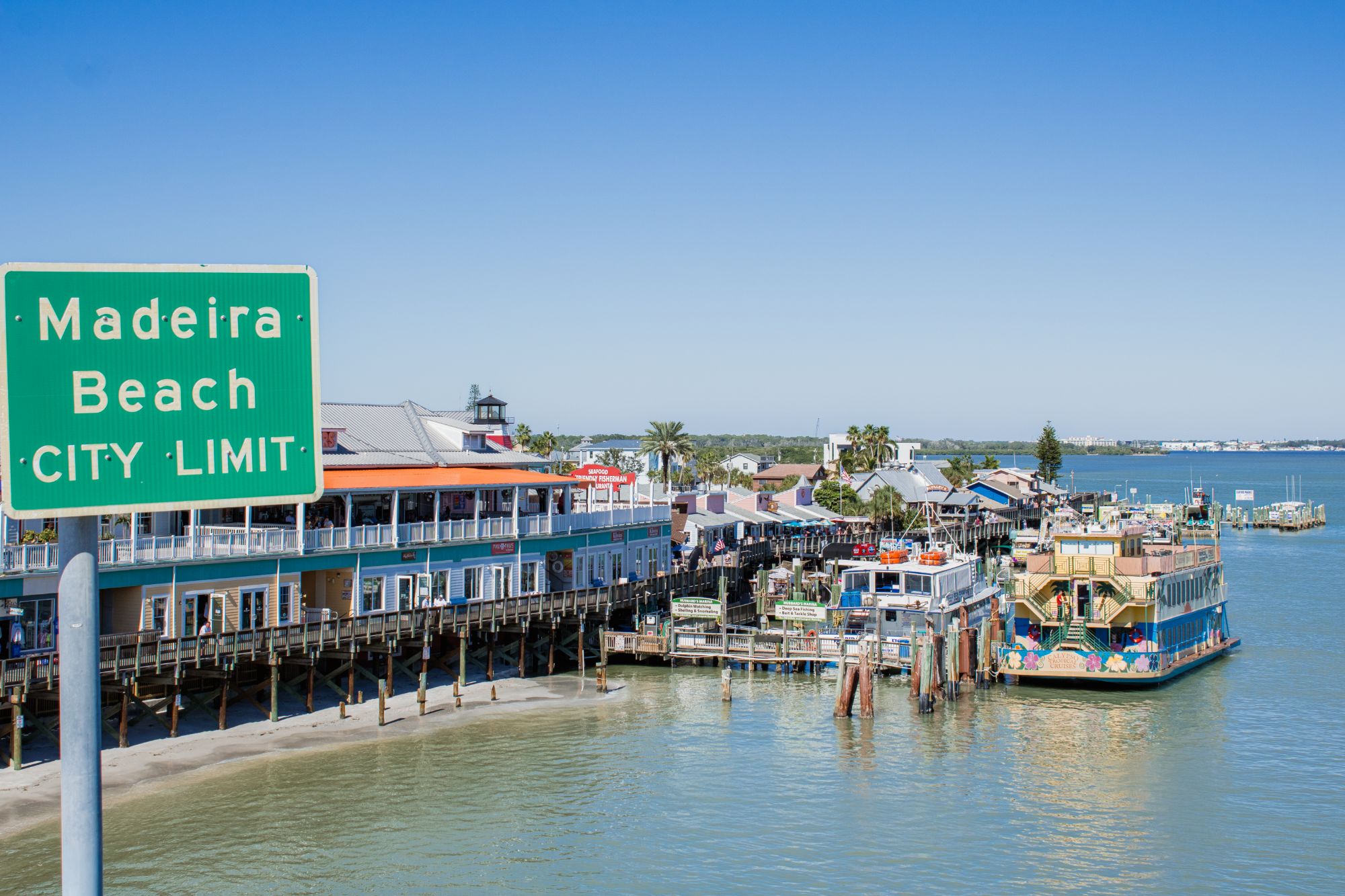 John's Pass Village boardwalk and marina beside the Madeira Beach city limit sign in Madeira Beach, FL
